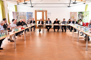 Teilnehmer des Runden Tisches sitzen an Tischen und diskutieren