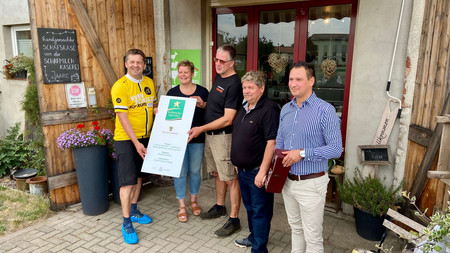 Minister Sven Schulze übergibt das Hofschild "Kulinarischer Stern" an die Inhaber der Schafmilchkäserei JAARE in Lindau.