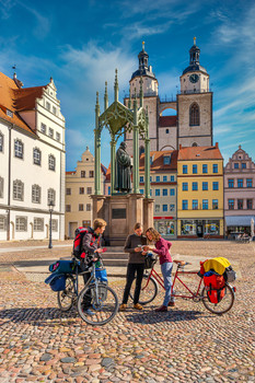Drei Radfahrer auf dem Marktplatz der Lutherstadt mit dem Martin-Luther-Denkmal im Hintergrund