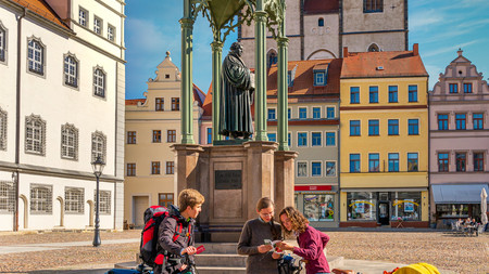 Lutherstadt Wittenberg Drei Radfahrer auf dem Marktplatz der Lutherstadt mit dem Martin-Luther-Denkmal im Hintergrund