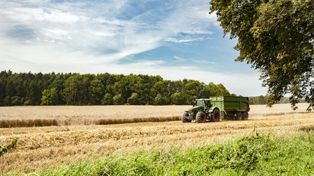 Traktor im Sommer auf einem gelben Getreidefeld