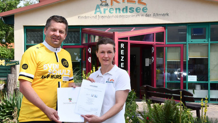 Minister Sven Schulze übergibt das Zertifikat "Reisen für Alle" an die Leiterin des KiEZ in Arendsee.