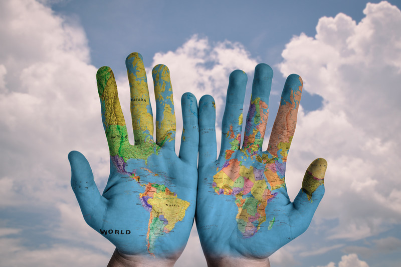 Das Bild zeigt zwei offene Hände, die mit einer Weltkarte blau bemalt sind.