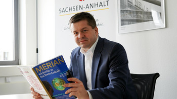 Tourismusminister Sven Schulze mit dem Merian-Reisemagazin zum Welterbe in Sachsen-Anhalt