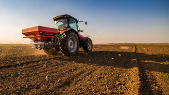 Ein Traktor versprüht Dünger auf einem Feld mit Jungpflanzen